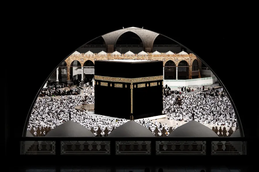The Kaaba viewed through an arched gallery of Masjid al-Haram, surrounded by worshippers