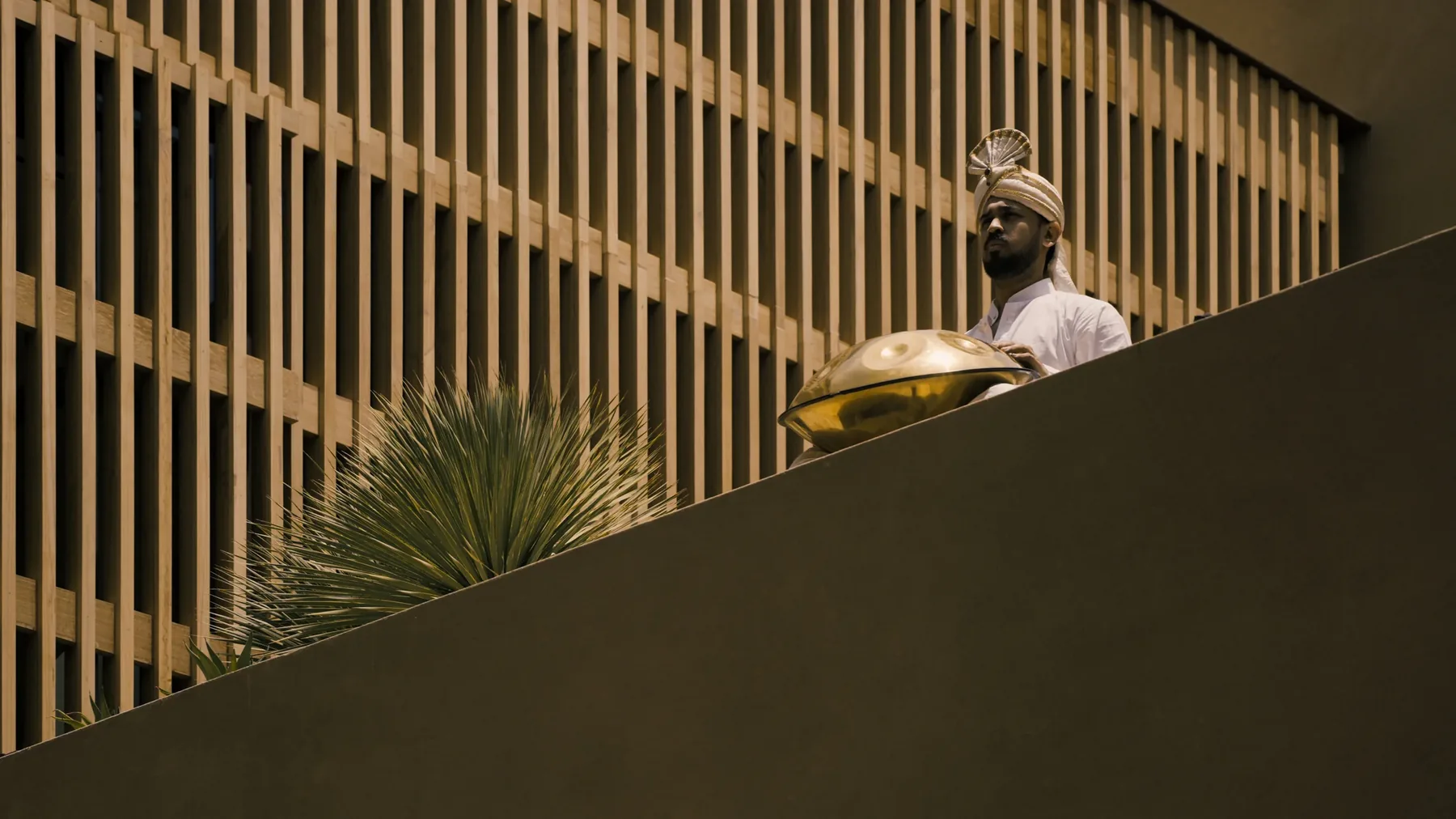 A figure carrying a brass tray behind the vertical timber screen