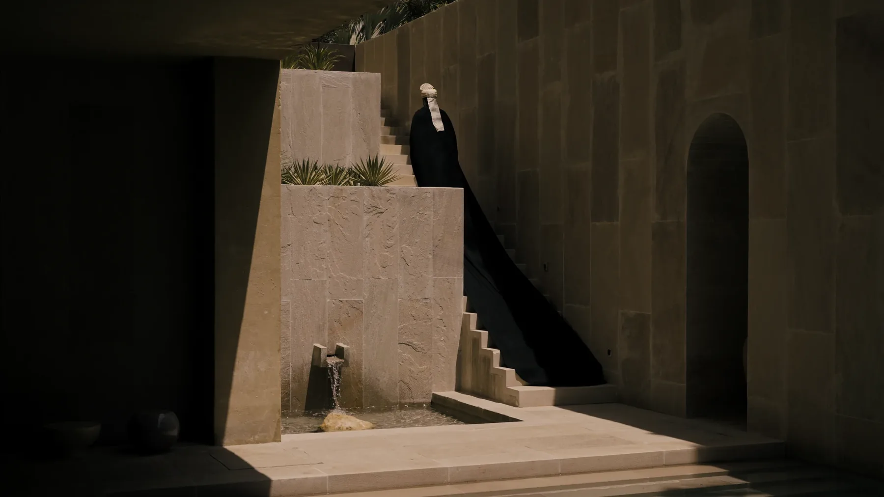 A figure descending the stair beside the water spout