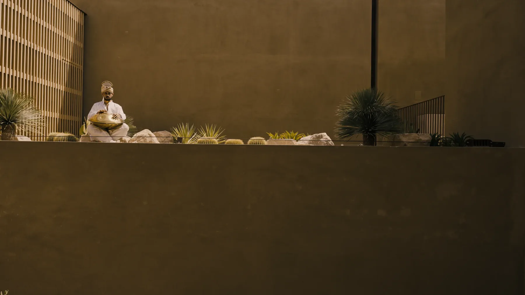 A seated figure holding a brass vessel on the planted ledge