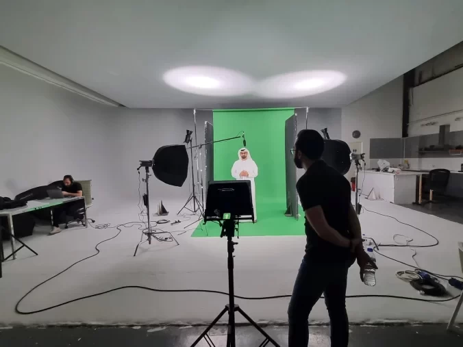 BTS image from a green screen film shoot showing crew, gear, and chroma key background in studio environment