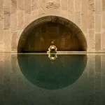 Fine art architectural photograph of the swimming pool at OrangeBox Villa with symmetrical stone arches and reflective water
