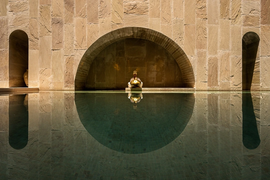 Fine art architectural photograph of the swimming pool at OrangeBox Villa with symmetrical stone arches and reflective water